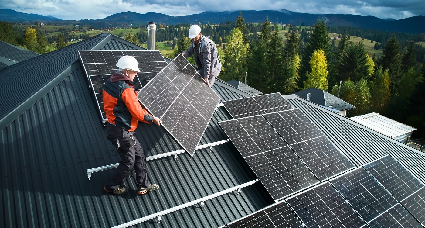 Mitarbeiter für Solaranlagentechnik beim Anbringen einer Solaranlage auf dem Dach